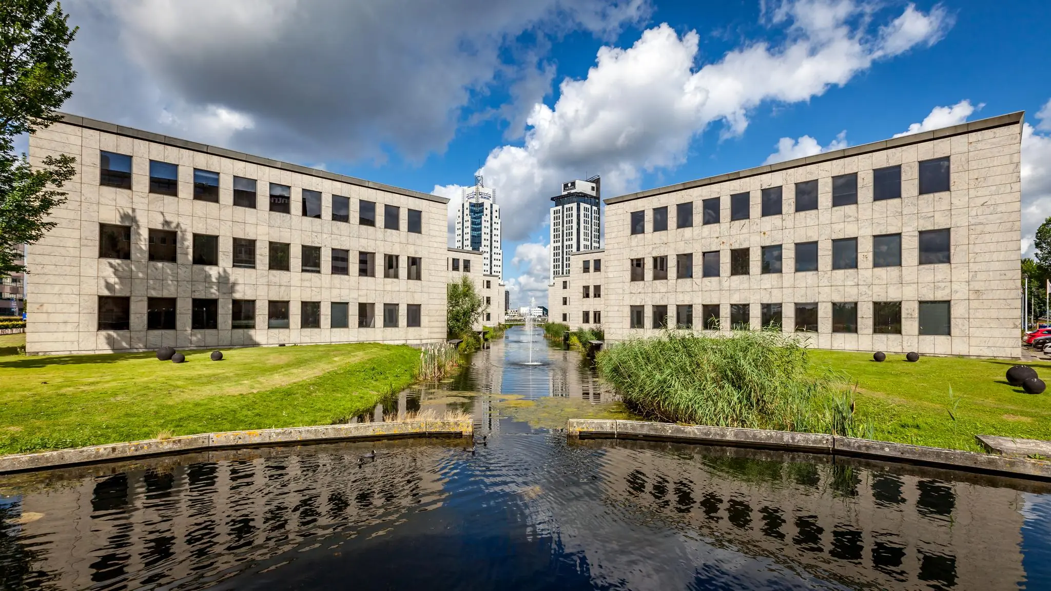 Modern kantoorgebouw aan de Rivium 1e Straat met symmetrische architectuur en een waterpartij met fontein op de voorgrond.